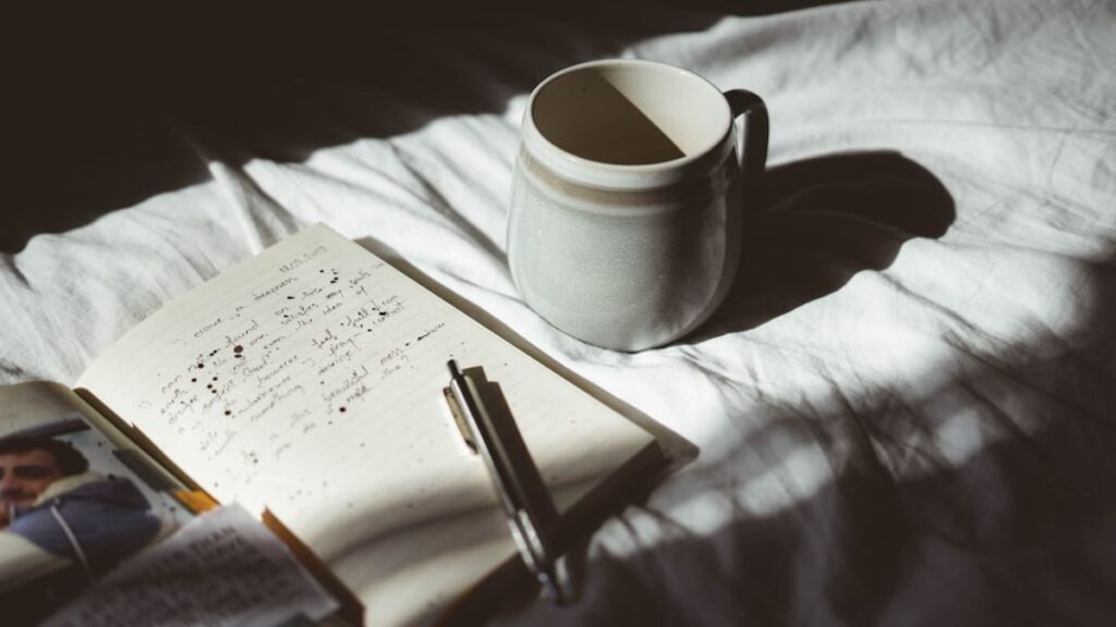 Uma pilha de livros com capas diversas, alguns abertos, sobre uma superfície de madeira, com um fundo desfocado que sugere uma biblioteca ou livraria.